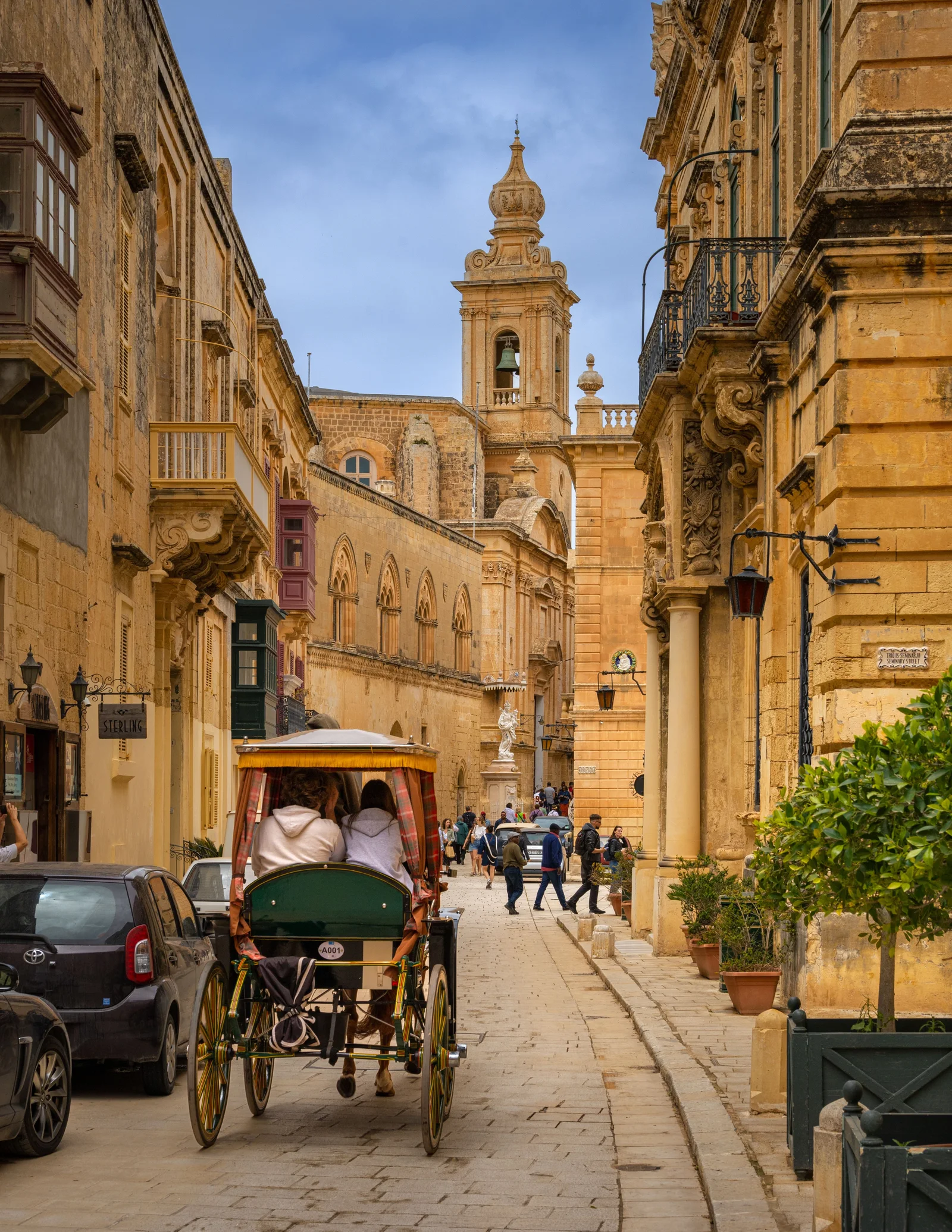People enjoy a horse-drawn carriage ride on an ancient street in Mdina, Malta.