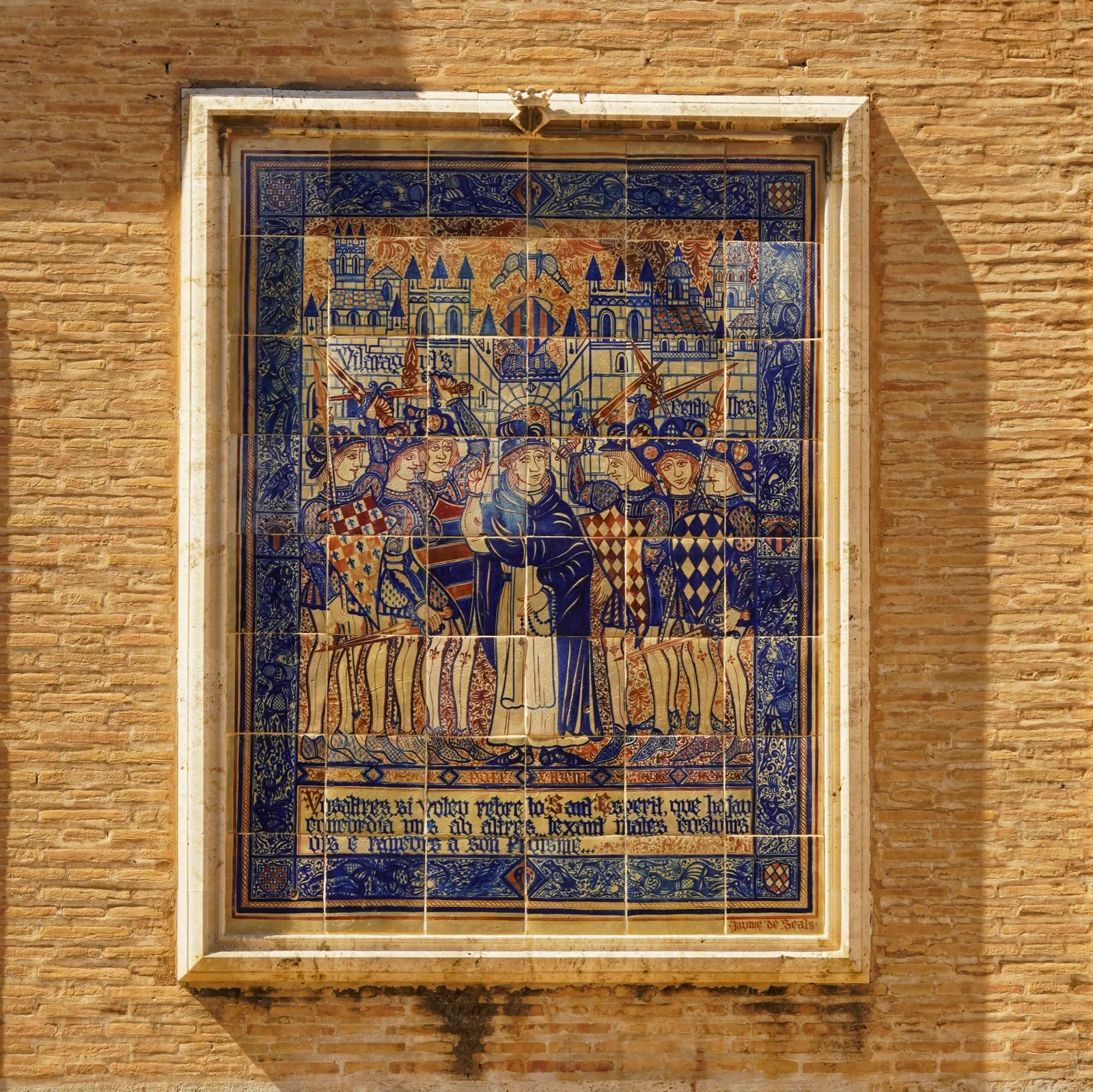 Colorful medieval tile mural on a historic brick wall in Valencia, Spain.