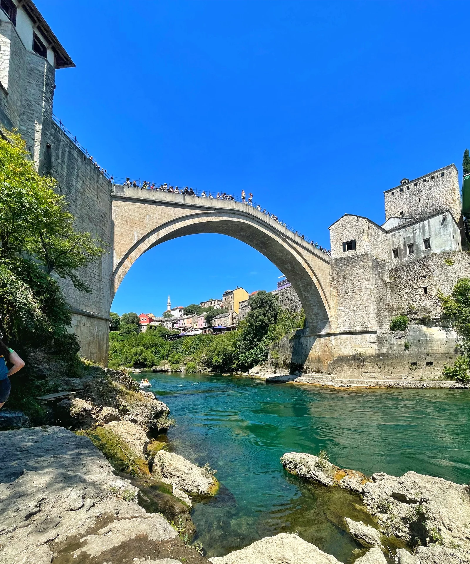 View of the historic Stari Most Bridge in Mostar, Bosnia, during a bright summer day.