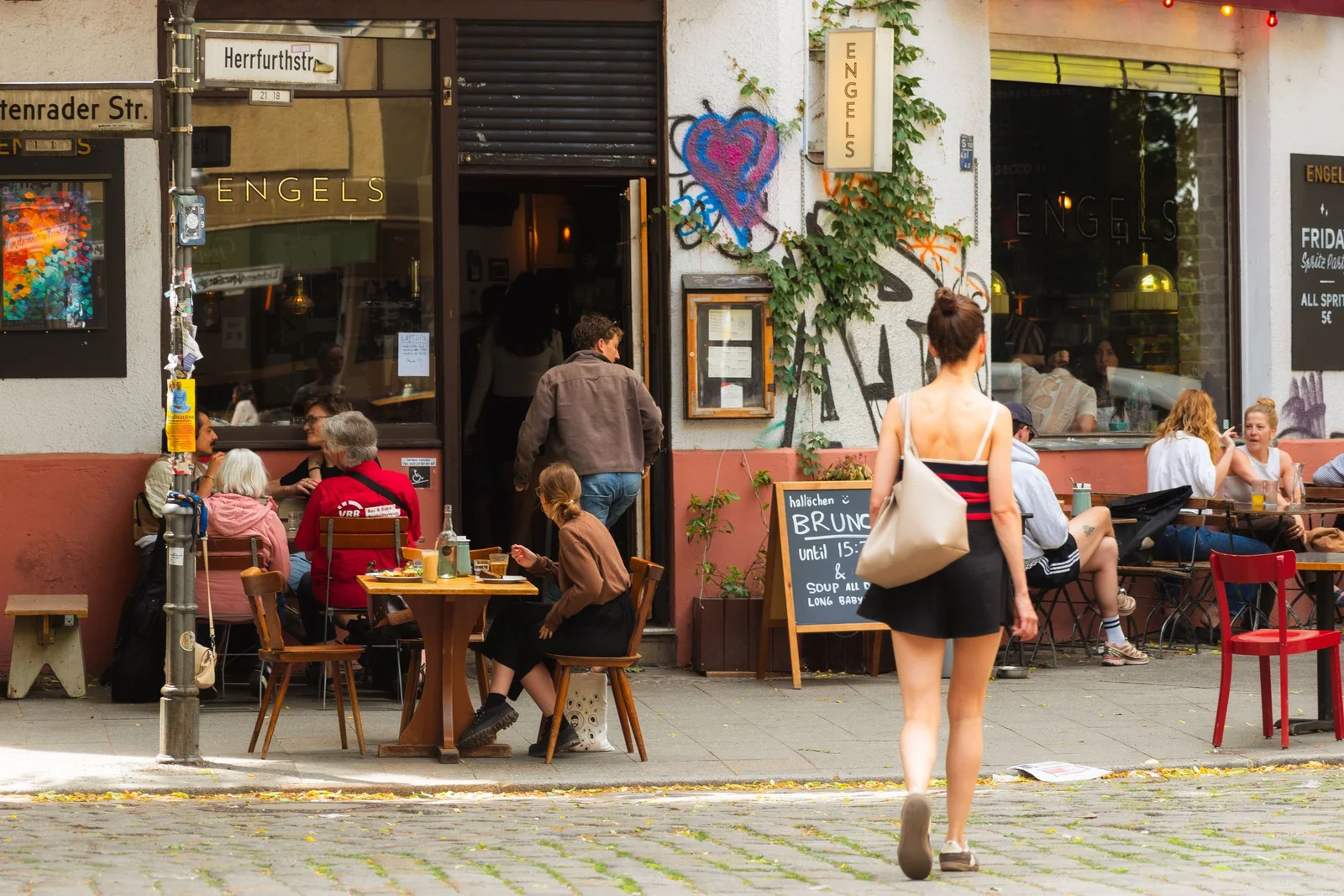 Lively outdoor cafe scene with people enjoying brunch in sunny weather.