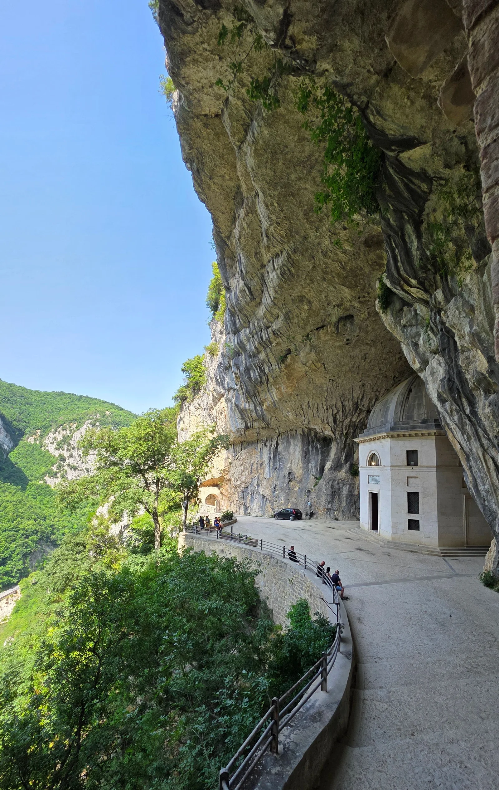Spectacular sanctuary built into a mountain cliff, surrounded by lush greenery and panoramic views.
