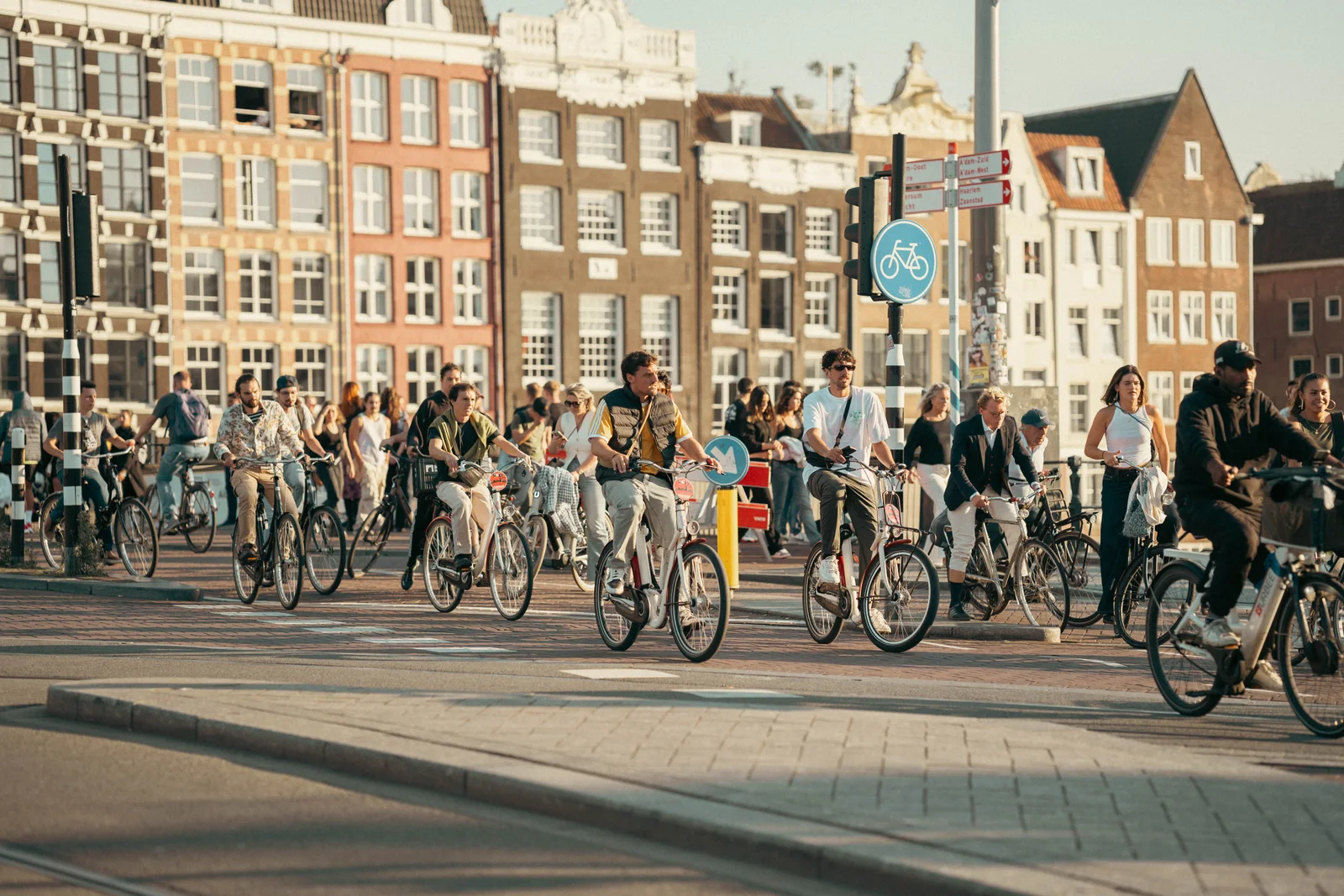 A vibrant scene of people cycling through Amsterdam under the bright sun.